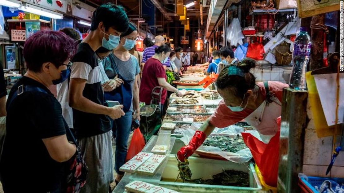 Un grupo de personas usan máscaras faciales mientras compran en un puesto de pescado dentro de un mercado húmedo el 25 de julio de 2020 en Hong Kong, China.