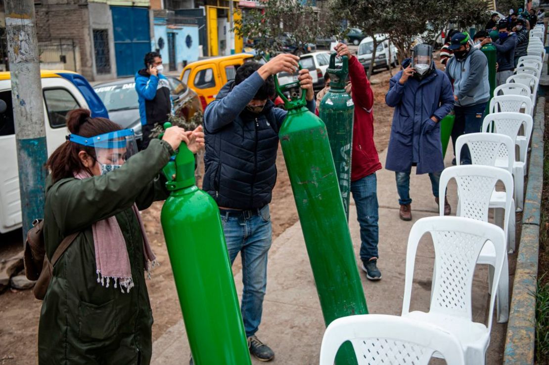 Familiares de pacientes con covid-19 hacen fila para recargar los cilindros de oxígeno en Villa María del Triunfo, en Lima.