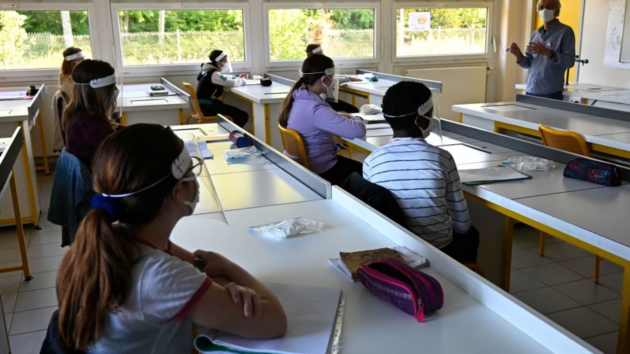 Schoolchildren wearing protective mouth masks and face shields listen to their teacher in a classroom at Claude Debussy college in Angers, western France, on May 18, 2020 after France eased lockdown measures to curb the spread of the COVID-19 pandemic, caused by the novel coronavirus. (Photo by Damien MEYER / AFP)