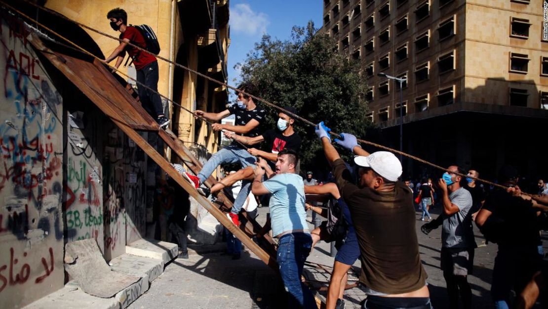 Los manifestantes escalan las paredes que sellan la plaza del parlamento en Beirut.