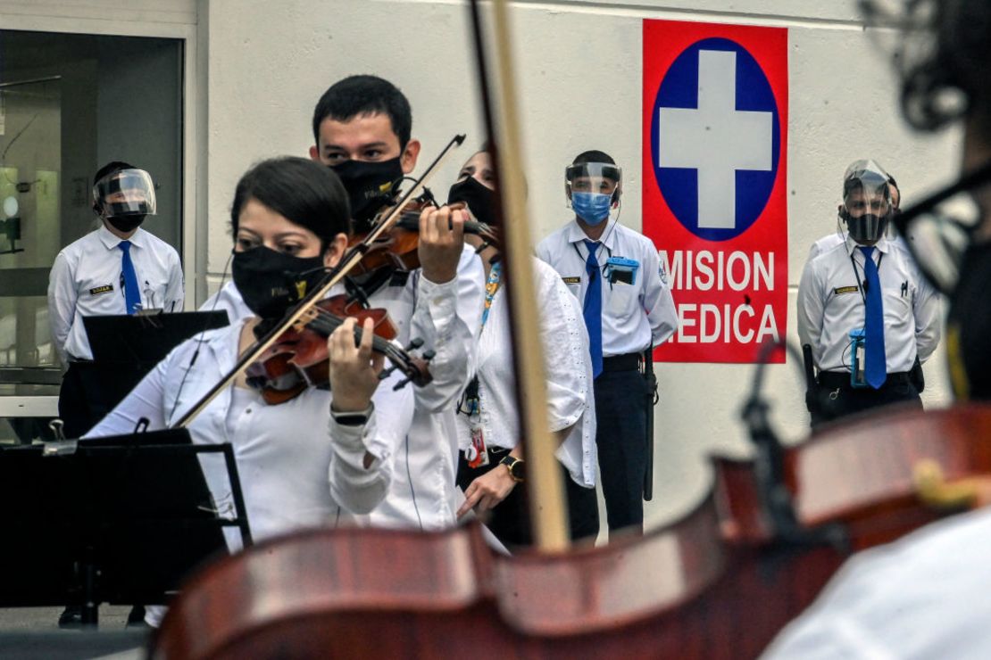 Músicos de la Orquesta Filarmónica de Medellín tocan para pacientes y trabajadores médicos frente a un hospital de la ciudad.