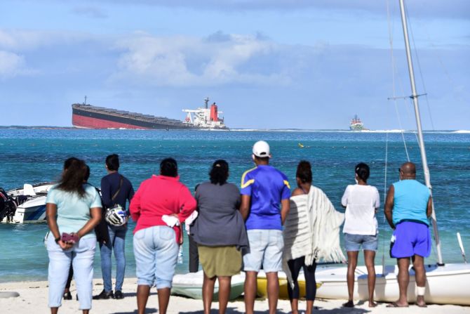 "Miles de especies alrededor de las lagunas vírgenes de Blue Bay, Pointe d'Esny y Mahebourg corren el riesgo de ahogarse en un mar de contaminación, con terribles consecuencias para la economía, la seguridad alimentaria y la salud de Mauricio ", dijo Happy Khambule, director de campaña de Greenpeace África. En esta foto, transeúntes miran el barco MV Wakashio desde la costa, el 6 de agosto.