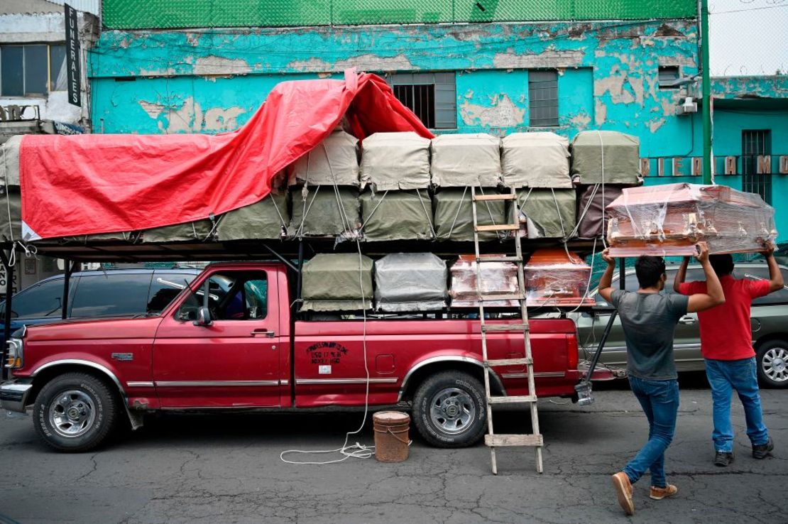 Trabajadores descargan ataúdes de una camioneta fuera de una funeraria al frente del Hospital General en Ciudad de México.