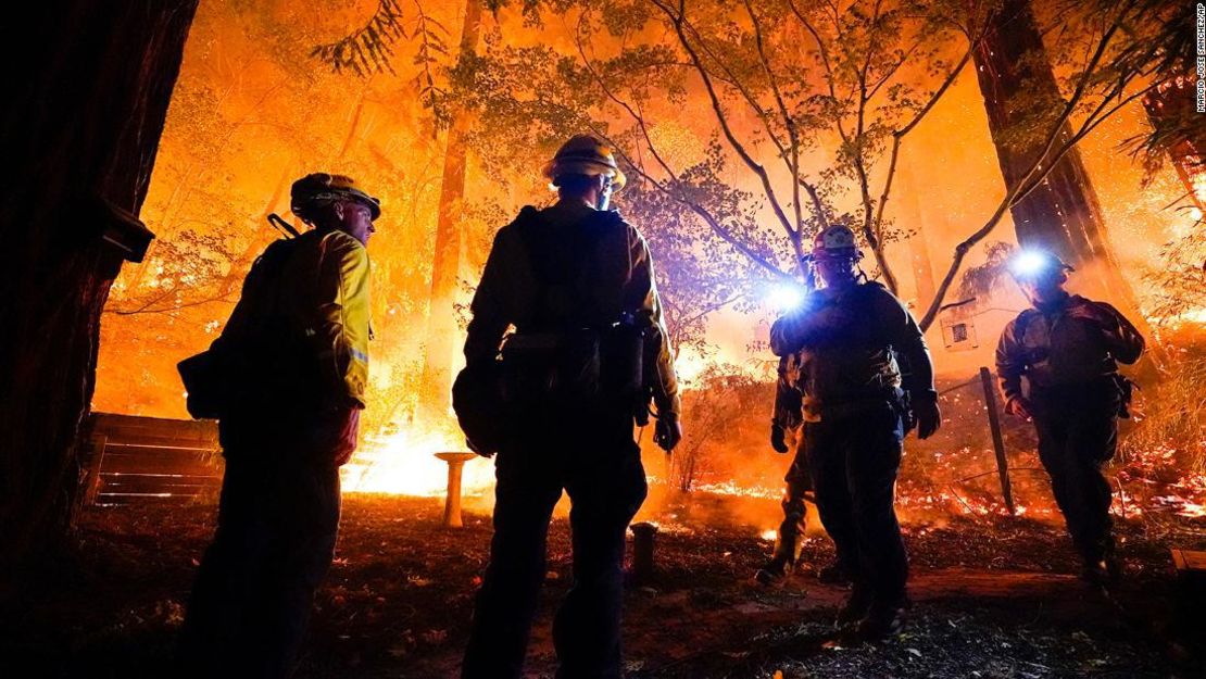 Bomberos en el patio trasero de una casa frente al incendio del Complejo CZU August Lightning, que avanza el viernes 21 de agosto en Boulder Creek, California.