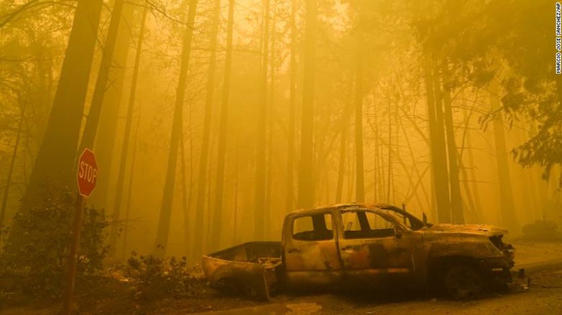 Un vehículo quemado frente a una residencia devastada por el fuego, mientras el humo llena el cielo el sábado 22 de agosto en Boulder Creek, California.