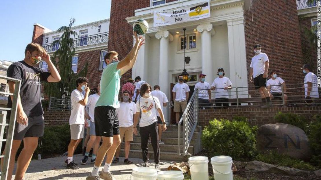 Estudiantes de la Universidad de Idaho usan máscaras faciales mientras juegan fuera de la fraternidad Sigma Nu durante el último día del proceso de reclutamiento, en agosto.