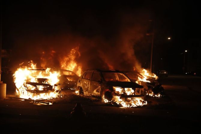 Llamas en autos incendiados por los manifestantes a pocas cuadras del Palacio de Justicia del condado.