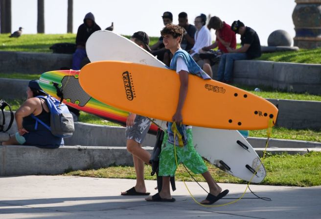 Dos hombres llevan tres tablas de surf en Venice Beach, California, el 4 de septiembre de 2020.