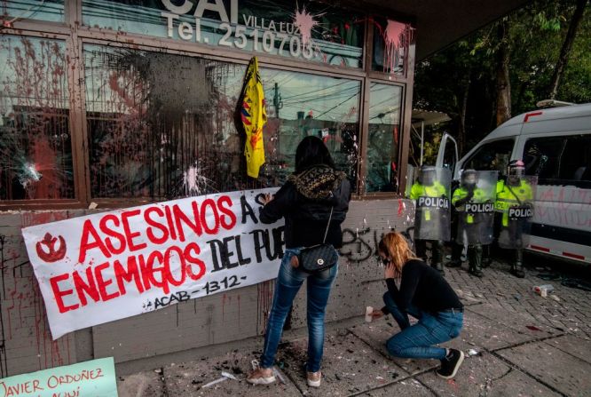 Una mujer pega una pancarta en un Comando de Acción Inmediata (CAI) de la policía en Bogotá.