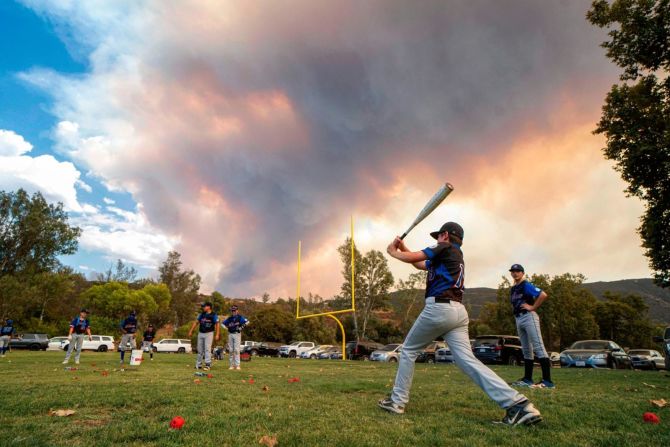 Jugadores de béisbol de las ligas menores calientan para un juego cerca de Dehesa, California, mientras el incendio Valley arde, el 6 de septiembre. Sandy Huffaker / AFP / Getty Images