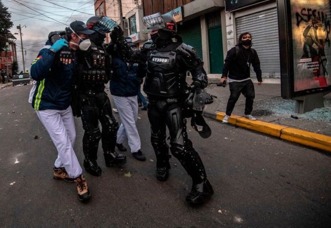 Paramédicos ayudan a un agente de policía antidisturbios herido.