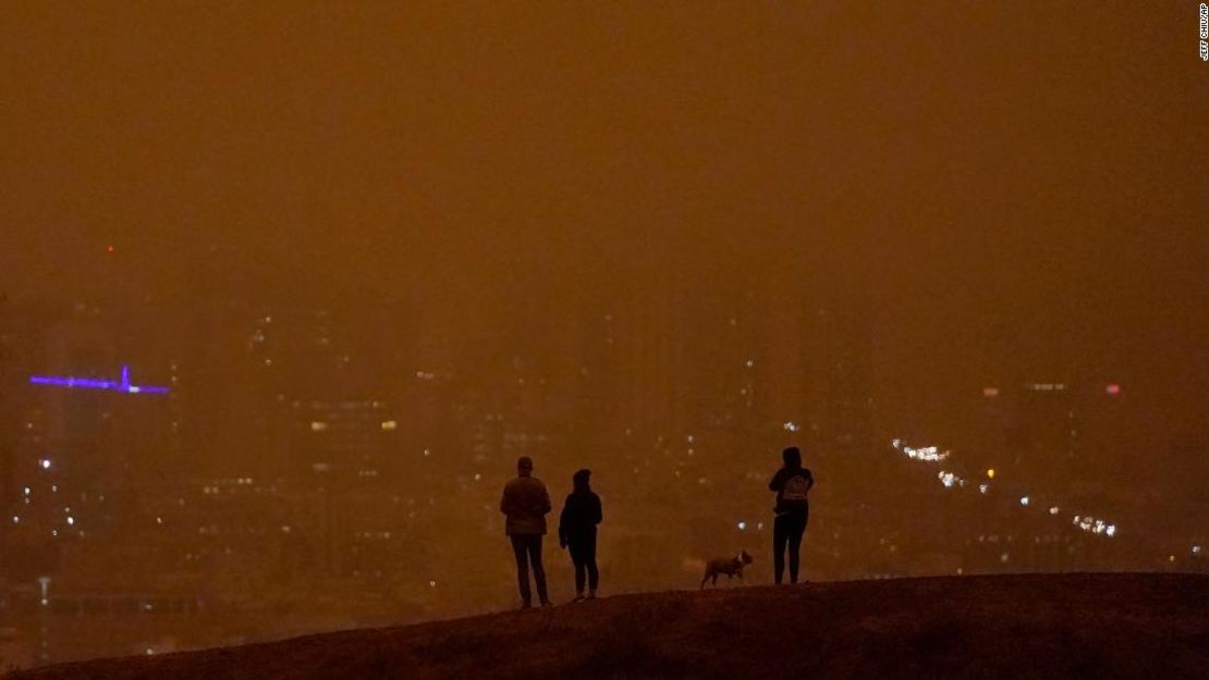 La gente mira hacia el horizonte oscurecido por el humo de los incendios forestales durante el día desde Kite Hill Open Space en San Francisco el 9 de septiembre.