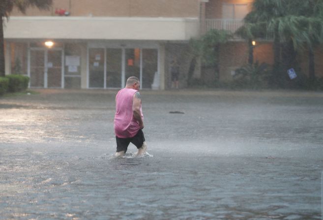 Un hombre camina por un estacionamiento inundado luego de que las bandas exteriores de Sally llegaran a tierra en Gulf Shores, Alabama, el 15 de septiembre de 2020.