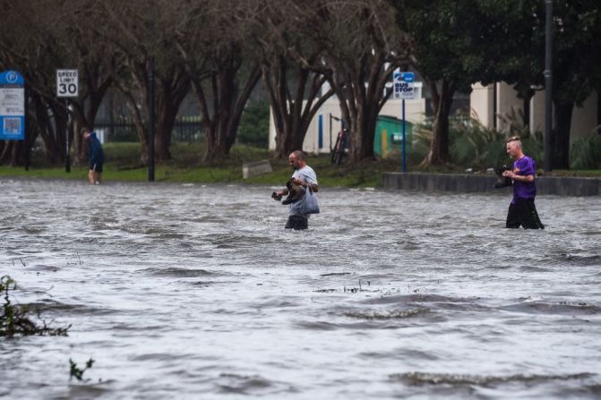 Personas cruzan una calle inundada por Sally en Pensacola, Florida, el 16 de septiembre de 2020.