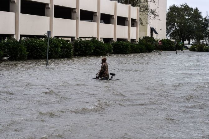 Un hombre camina con su bicicleta por una calle inundada en Pensacola, Florida, el 16 de septiembre de 2020, mientras Sally provoca fuertes lluvias y vientos.