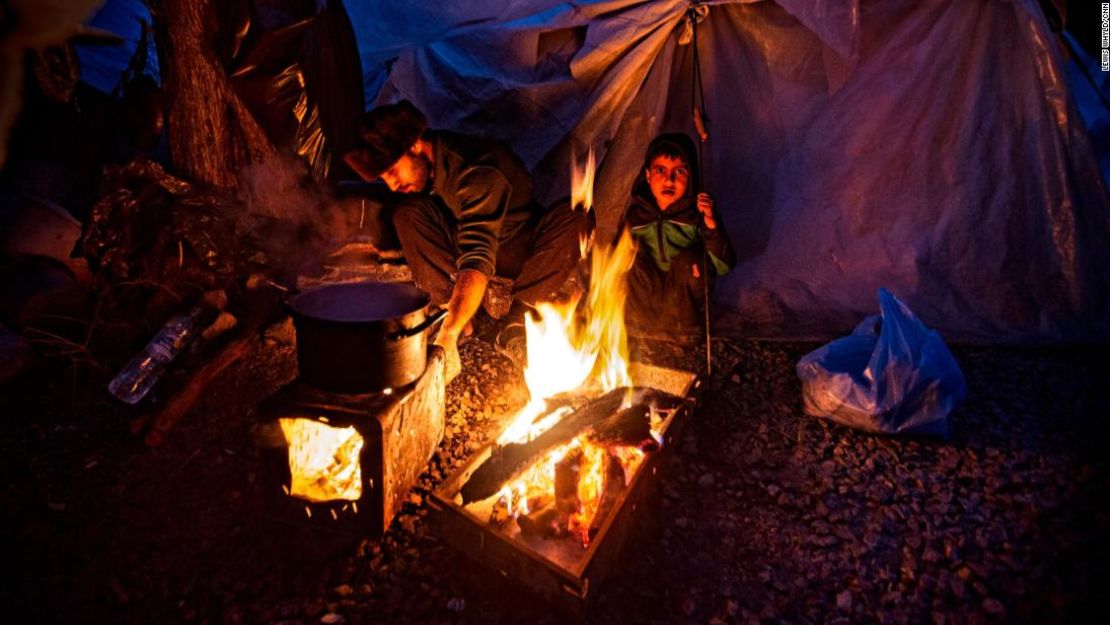 La gente se reúne alrededor de un fuego para calentarse en el campo de refugiados de Moria en Lesbos, Grecia, en febrero de 2020.