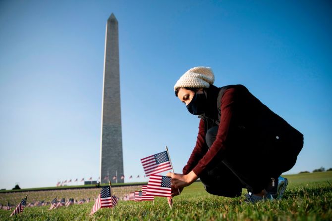 Una mujer clava una bandera en el National Mall en Washington en conmemoración a los 200.000 estadounidenses que han muerto por covid-19.