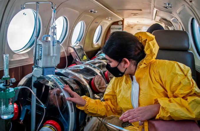 Andrea Lara mira a su padre, Juan Carlos Lara, de 59 años, un paciente con covid-19 que estaba siendo transferido dentro de una cápsula de seguridad en una ambulancia aérea desde Iquitos a la unidad de cuidados intensivos en el hospital Rebagliati en Lima.