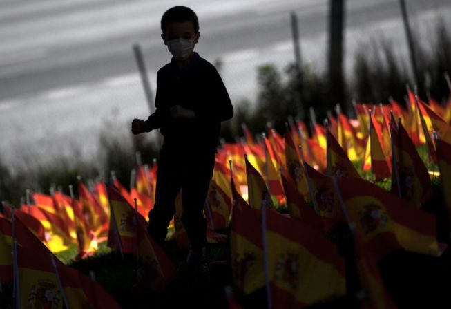 Un niño corre entre las miles de banderas españolas que conmemoran a las víctimas de covid-19 en el parque Roma en Madrid. OSCAR DEL POZO/AFP via Getty Images)