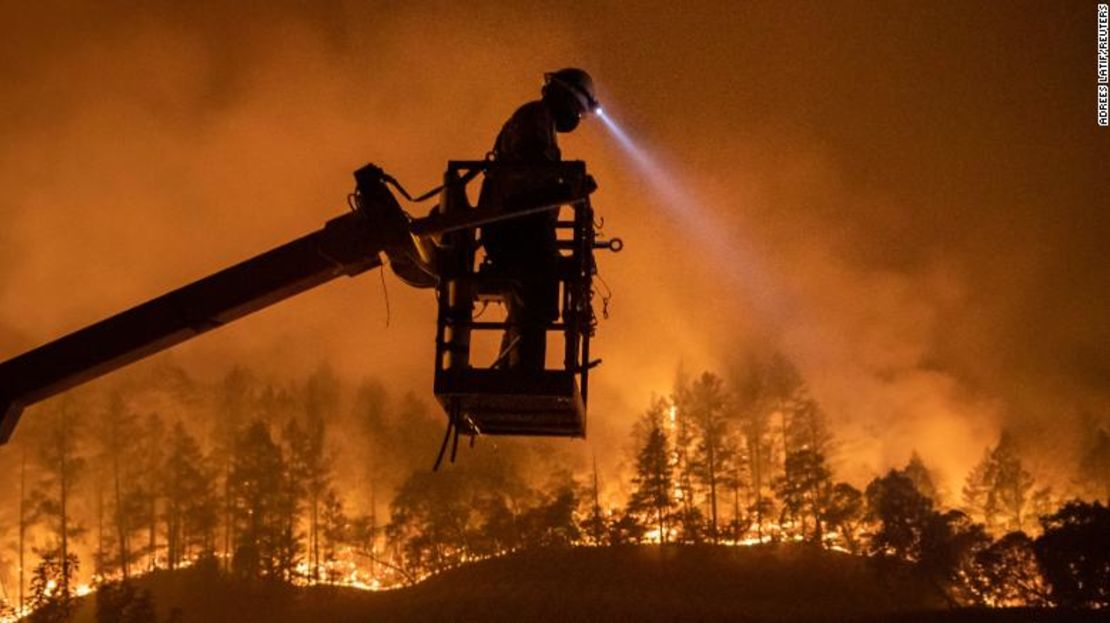 El incendio Glass arde mientras Josh Asbury, un empleado de CableCom, instala fibra óptica en Calistoga, California, el 28 de septiembre de 2020.