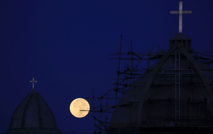 La luna llena fotografiada detrás de una iglesia en construcción en las afueras de Chandigarh, en India, el 2 de octubre de 2020. (Vijay Mathur/ AFP/ Getty Images).