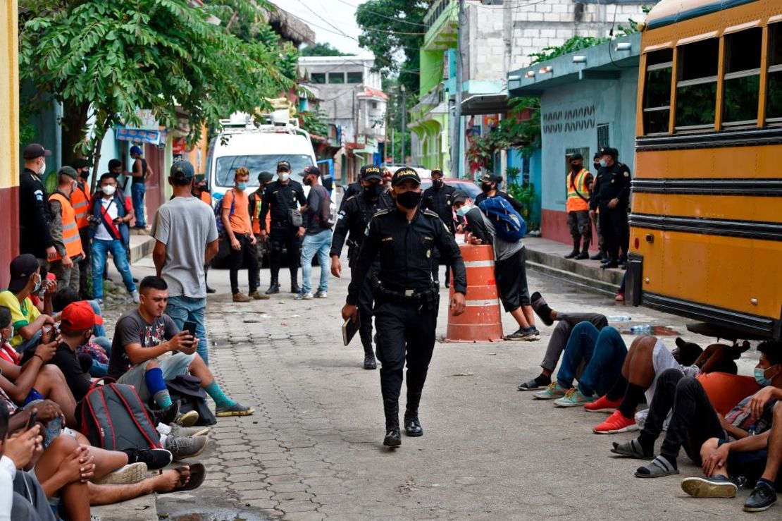 Policías pasan junto a un grupo de migrantes hondureños, parte de una caravana de migrantes con destino a Estados Unidos, frente a un refugio para migrantes en el municipio de San Marcos, Guatemala, el 3 de octubre de 2020. - México ordenó el viernes a los militares desplegarse a lo largo de su frontera sur bloquear una caravana de migrantes. Crédito: ALFREDO ESTRELLA/AFP via Getty Images