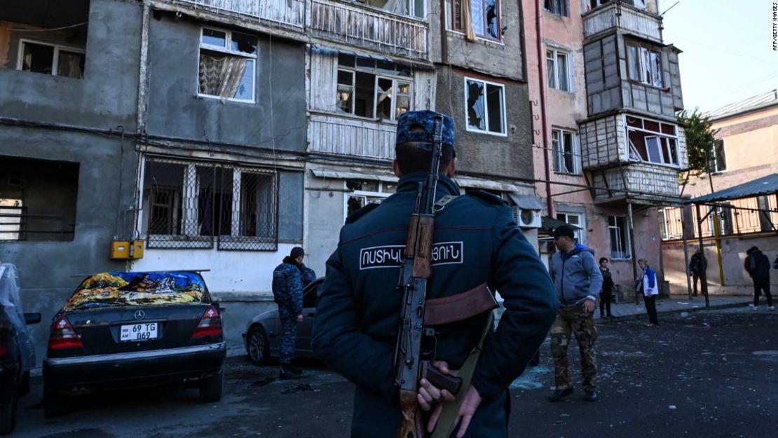 Un policía está parado frente a un edificiodañado en Stepanakert durante el conflicto en curso.