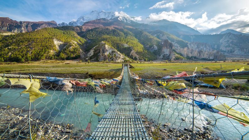 10. Circuito de Annapurna, Nepal: la nueva edición de la lista de viajes de Lonely Planet incluye muchos destinos de visita imperdibles, como el circuito Annapurna de Nepal. Caminando por este terreno, pasarás por arrozales, praderas de yak y un paso de montaña nevado. En la foto: un puente colgante con banderas de oración budistas.