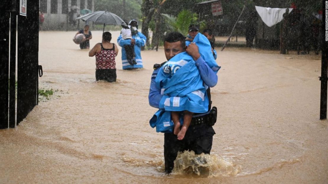 Agentes de la Policía y residentes rescatan a niños el miércoles en la ciudad de El Progreso, ubicada en el departamento hondureño de Yoro.