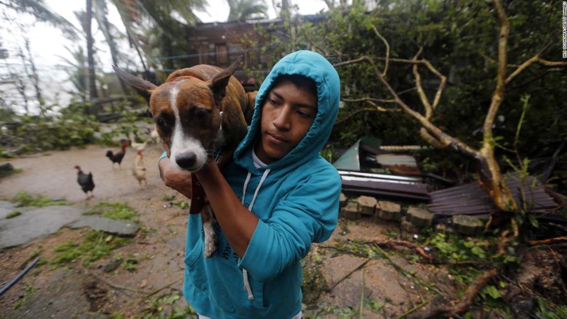 Un hombre lleva a un perro a un lugar seguro después de que Eta golpea a Nicaragua.