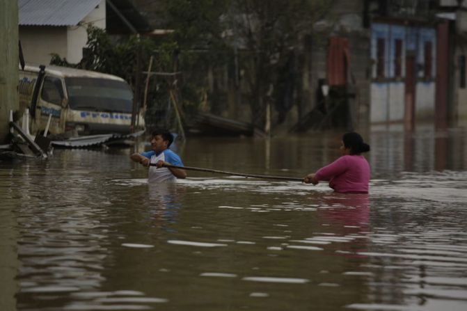 Un hombre ayuda a una mujer a cruzar por una calle inundada durante la inundación del 8 de noviembre de 2020 en Cobán, Guatemala. Eta azotó Guatemala como una tormenta tropical que provocó inundaciones, lluvias torrenciales y deslizamientos de tierra. Cobán es uno de los municipios más afectados, las rutas de acceso por tierra están bloqueadas por deslizamientos de tierra y la ayuda ha sido difícil de llevar.