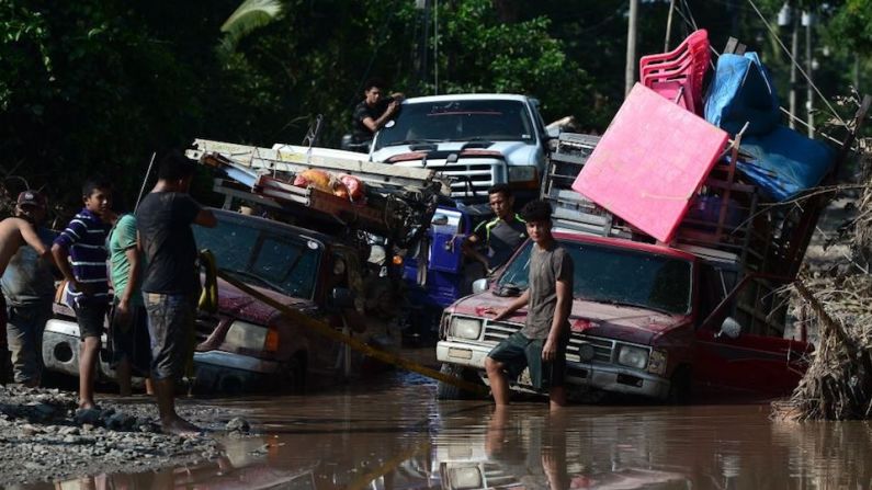 Trabajadores de los campos bananeros se encuentran con una carretera inundada mientras evacuan el área en El Progreso, departamento de Yoro, Honduras, el 14 de noviembre de 2020, antes de la llegada de la tormenta tropical Iota.