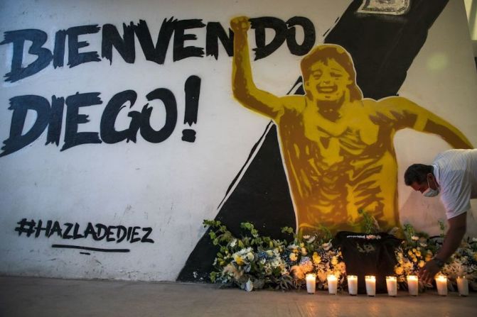 Un hombre enciende una vela debajo de un mural de Diego Maradona mientras seguidores de la leyenda del fútbol argentino se reúnen frente al Estadio Banorte en Culiacán, estado de Sinaloa, México, el 25 de noviembre de 2020. Maradona fue entrenador de los Dorados de Sinaloa.