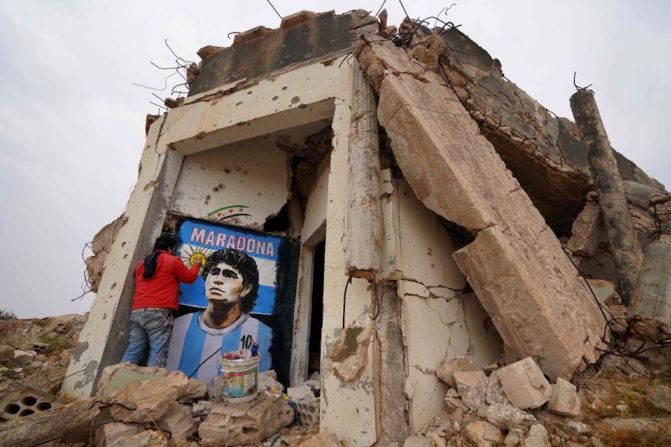 El pintor sirio Aziz Asmar dibuja en la pared de una casa destruida un retrato del famoso futbolista argentino Maradona en la ciudad de Binnish, provincia de Idlib, noroeste de Siria.