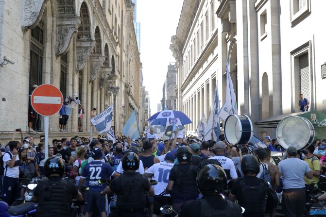 Seguidores de Gimnasia y Esgrima de La Plata cantan y agitan banderas mientras la policía intenta contenerlos cerca de la Plaza de Mayo el 26 de noviembre de 2020 en Buenos Aires, Argentina.