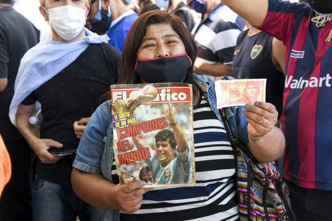 Una seguidora de Maradona sostiene una revista de El Gráfico de la Copa del Mundo de 1986 y un billete cubano del 'Che' Guevera mientras hace cola para entrar a la Casa Rosada el 26 de noviembre de 2020 en Buenos Aires, Argentina.