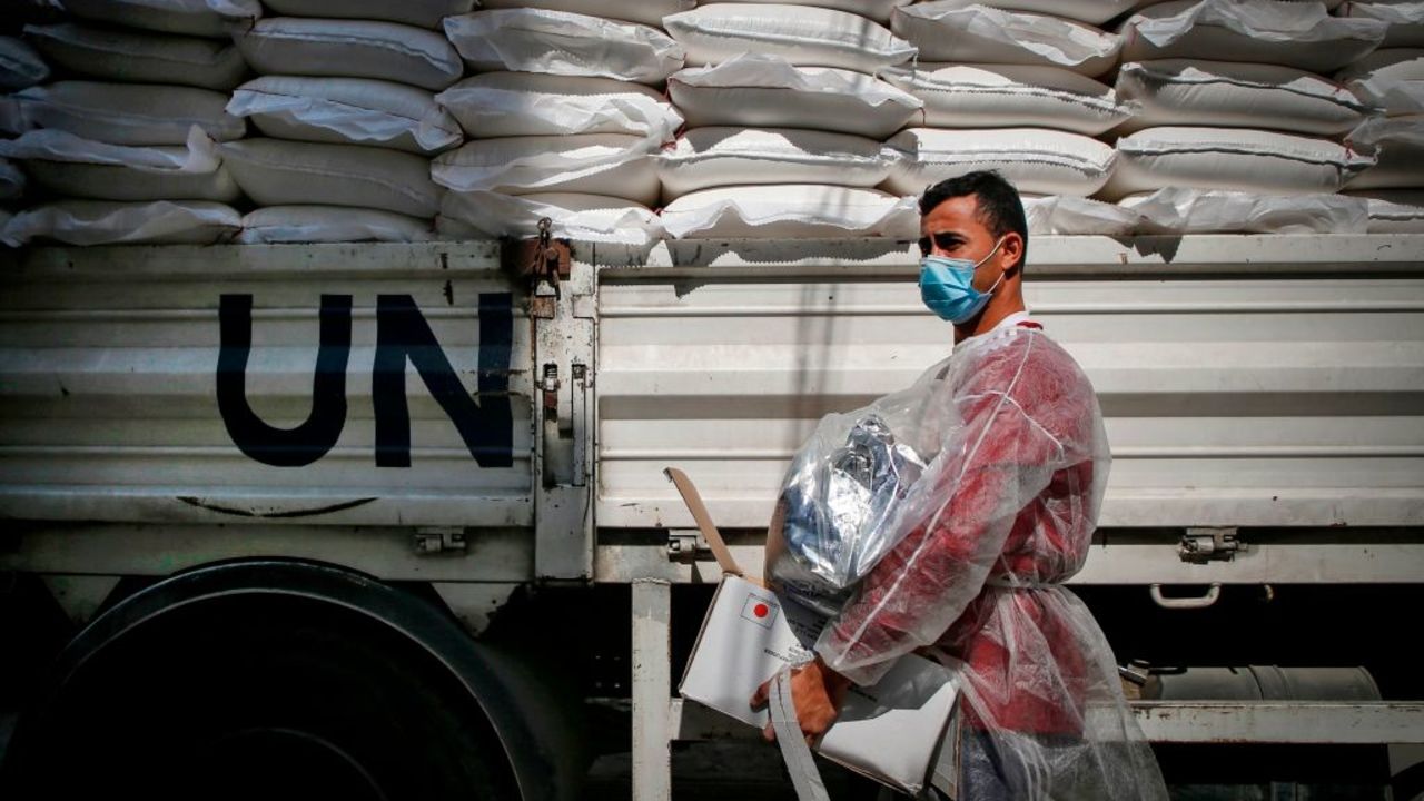 A worker of the United Nations Relief and Works Agency for Palestine Refugees (UNRWA), clad in mask and protective gear due to the COVID-19 coronavirus pandemic, delivers food aid to families in need in Gaza City on September 15, 2020. (Photo by MOHAMMED ABED / AFP)