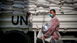 A worker of the United Nations Relief and Works Agency for Palestine Refugees (UNRWA), clad in mask and protective gear due to the COVID-19 coronavirus pandemic, delivers food aid to families in need in Gaza City on September 15, 2020. (Photo by MOHAMMED ABED / AFP)