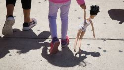 A 4-year-old Honduran girl carries a doll while walking with her immigrant mother, both released from detention through the "catch and release" policy, from a Catholic Charities relief center to a nearby bus station on June 17, 2018 in McAllen, Texas. - "Catch and release" is a protocol under which people detained by US authorities as unlawful immigrants can be released while they wait for a hearing. (Photo by Loren ELLIOTT / AFP)