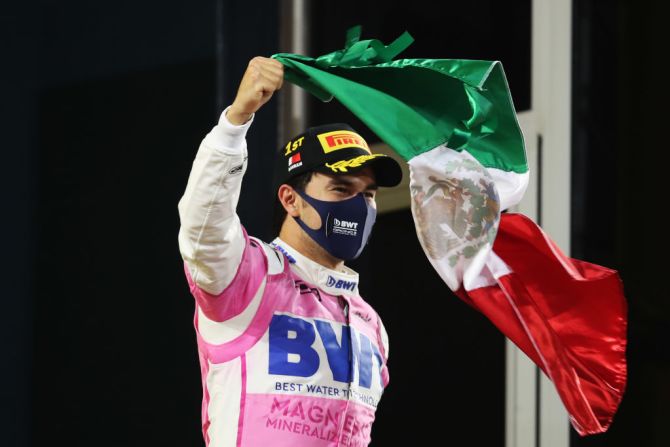 El ganador de la carrera celebra en el podio ondeando la bandera de México. Crédito: Tolga Bozoglu - Pool / Getty Images