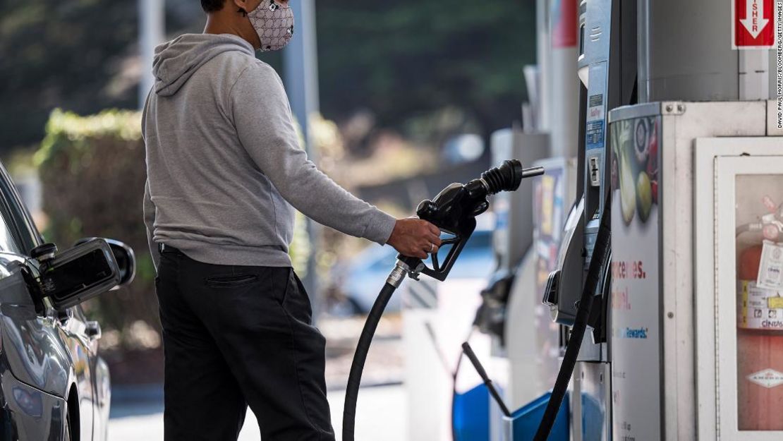 Una persona con una máscara protectora sostiene una boquilla de una estación de combustible, mientras recarga gasolina en una estación de servicio de Chevron Corp en Colma, California, el 24 de septiembre de 2020.