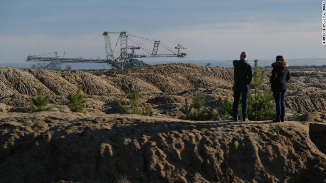 Los visitantes miran una máquina gigante llamada esparcidor que arroja tierra cerca de una mina de carbón a cielo abierto en Neupetershain, Alemania.