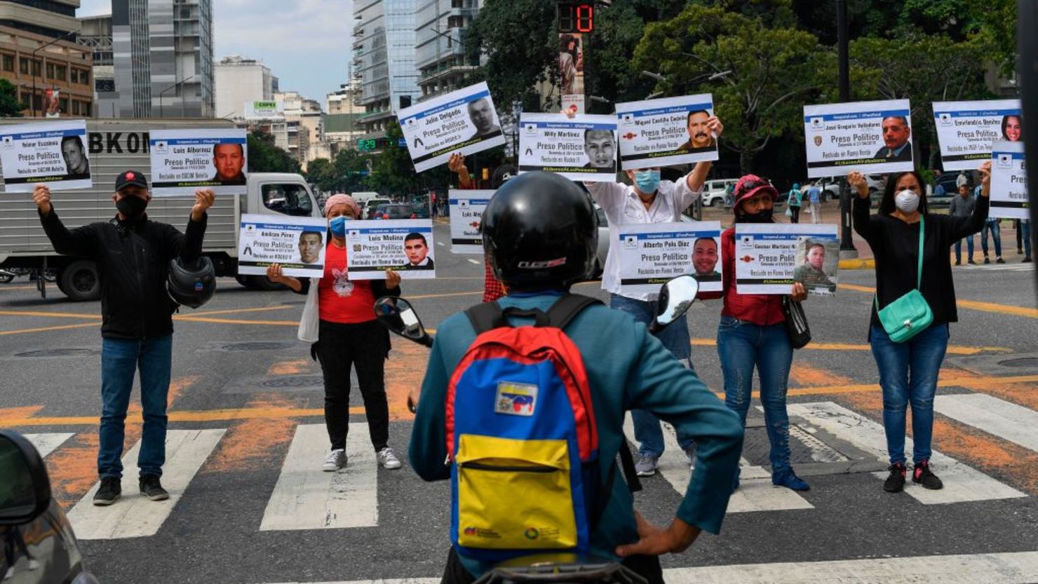 Familiares de opositores al gobierno que permanecen detenidos en diferentes cárceles sostienen carteles con sus retratos y nombres durante una protesta convocada por la ONG de derechos humanos Foro Penal en el marco de una campaña denominada "Navidad sin presos políticos" en un paso de peatones en Caracas el 10 de diciembre , 2020.