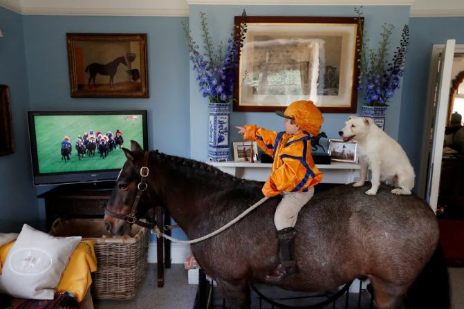 17 de junio –– Merlin Coles, de 3 años, se sienta en su caballo Mr. Glitter Sparkles y observa las carreras de caballos de Royal Ascot desde su casa en Bere Regis, Inglaterra. Junto a Merlin está su perro Mistress.