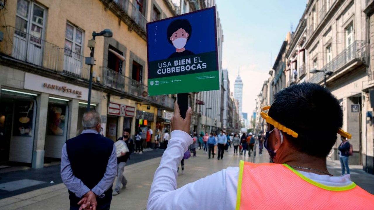 A Local Government employee wearing a face mask holds a banner reading "Use the face mask properly" in Madero street at the start of the Christmas season in Mexico City on December 1, 2020, amid the COVID-19 coronavirus pandemic. - Mexico City's government reported that the orange alert is still on due to the high number of COVID-19 infections that have been registered in the city. (Photo by ALFREDO ESTRELLA / AFP)