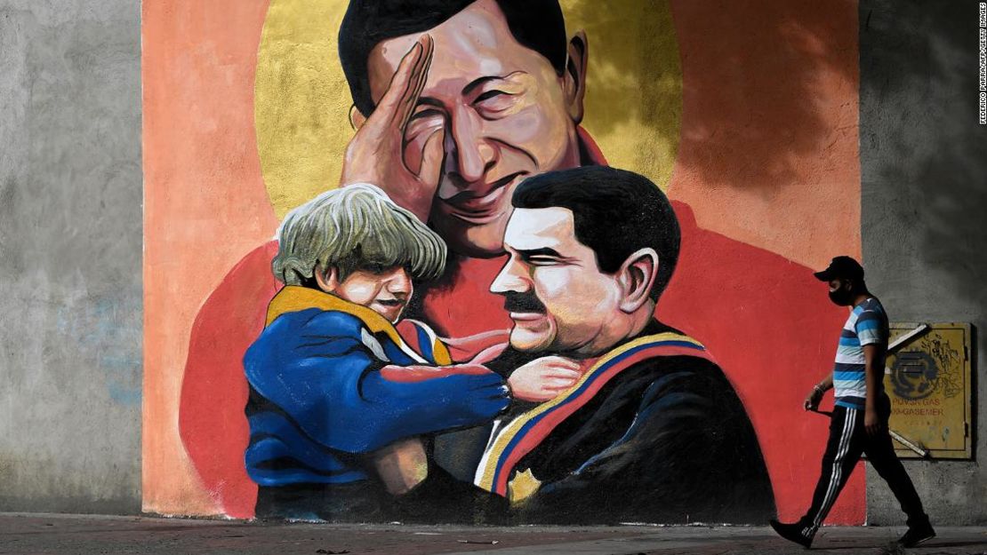 Un mural representa al difunto presidente Hugo Chávez saludando al presidente Nicolás Maduro, quien sostiene a un niño en sus brazos, en Caracas el 9 de diciembre de 2020.