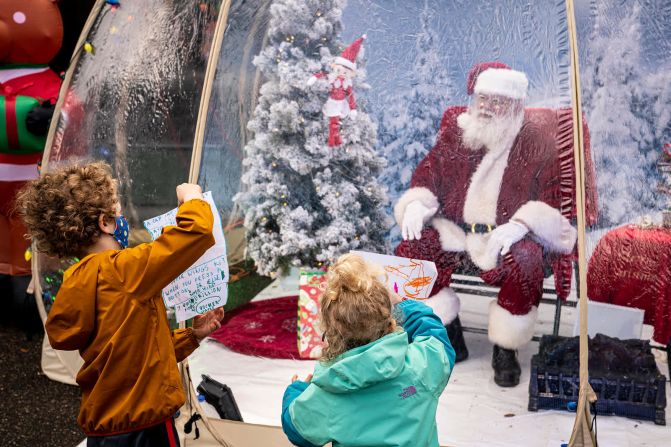 6 de diciembre: Mateo y Neah Johnson le muestran a Santa sus cartas mientras lo visitan en un globo de nieve socialmente distanciado en Seattle. Imágenes de David Ryder / Getty