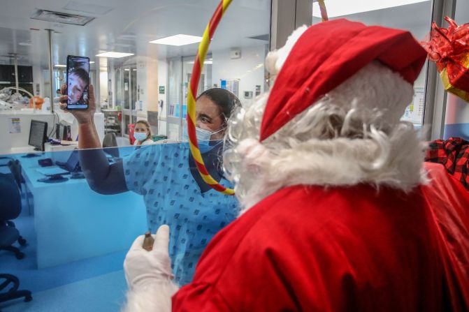 Un trabajador de la salud vestido de Papá Noel saluda a un niño a través de una pantalla de teléfono en un hospital de Cali, Colombia, el 24 de diciembre de 2020.