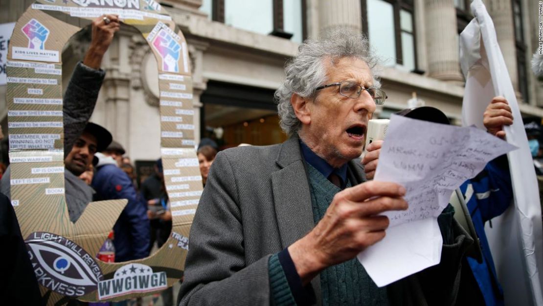 Piers Corbyn habla a los manifestantes mientras un hombre sostiene un cartel de QAnon detrás de él durante una protesta de StandUpX en Londres este octubre.