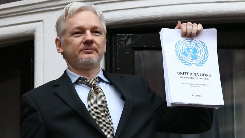Desde el balcón de la Embajada de Ecuador en Londres, Assange sostiene un informe de las Naciones Unidas en febrero de 2016. El Grupo de Trabajo de las Naciones Unidas sobre la Detención Arbitraria dijo que Assange estaba siendo detenido arbitrariamente por los gobiernos de Suecia y Reino Unido.